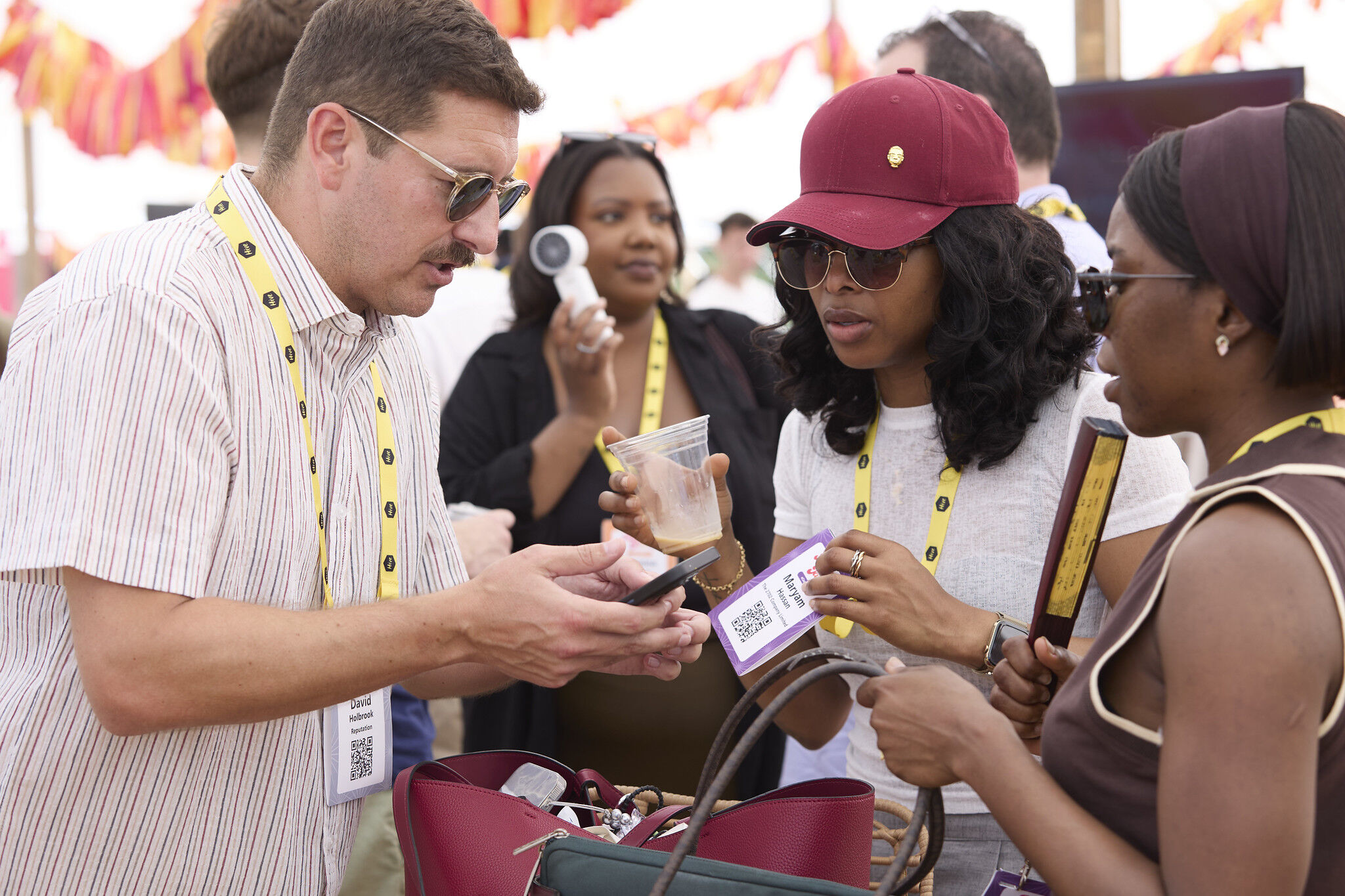 Event attendees wearing lanyards exchange contact details by scanning a QR badge at a festival.